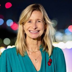Suzannah Nicol, CEO of Build UK, wearing a blouse with a red poppy pin and smiling.
